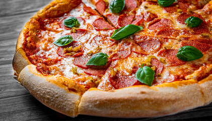 Pepperoni Pizza with Mozzarella cheese, salami, Tomato sauce, pepper, Spices and Fresh basil. Italian pizza on wooden table background