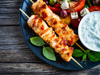Fried souvlaki, greek salad and tzatziki on wooden table