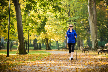 Nordic walking - middle-age woman working out in city park
