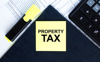 Yellow sticker with text Property Tax laying on the folder with yellow marker and calculator