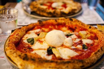 Delicious Italian pizza with mozzarella cheese, prosciutto, funghi (mushrooms) on the table at the local restaurant in the middle of Rome city, Lazio, Italy. European fast food and traditional dishes.