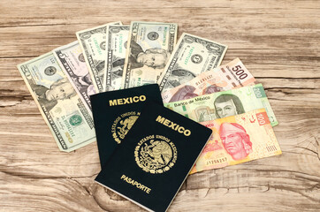 Pasaportes mexicanos y dinero, sobre una mesa de madera. Dólares americanos y pesos mexicanos.
