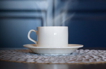 White cup of coffee on a wooden table, blurred background.