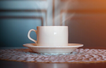 White cup of coffee on a wooden table, blurred background.