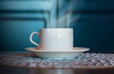 White cup of coffee on a wooden table, blurred background.