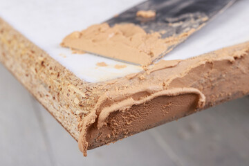 Filling chipboard with putty in a carpentry workshop. Small carpentry work in a home carpentry shop.
