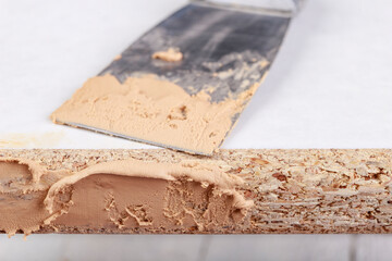 Filling chipboard with putty in a carpentry workshop. Small carpentry work in a home carpentry shop.