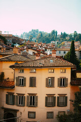 Fototapeta premium Close up. The street view of the old Italian colorful buildings with wooden shutters, tiled roofs, towers, shops in the city center of Bergamo, Lombardy, Italy. Vintage European architecture.