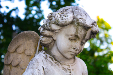 Figure of a praying angel. A very ancient stone statue. Death. Sad angel as symbol of pain, fear...