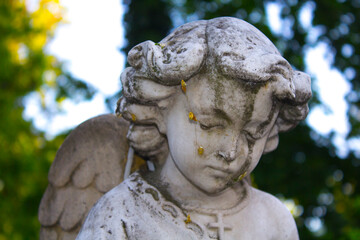 Figure of a praying angel. A very ancient stone statue. Death. Sad angel as symbol of pain, fear...