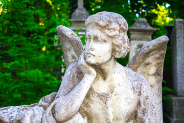 Figure of a praying angel. A very ancient stone statue. Death. Sad angel as symbol of pain, fear...