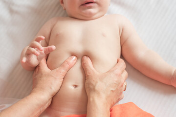 Massage stomach with colic for little child infant makes a doctor massage therapist in a massage...