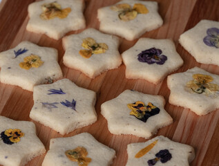 Star shaped biscuits decorated with edible flowers, pansies and cornflower petals. 