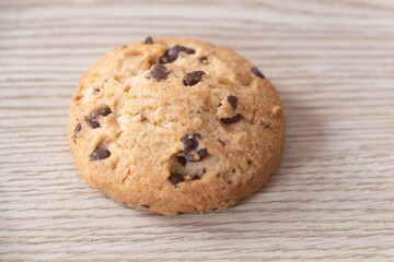 Cookie with chocolate chips on wooden background
