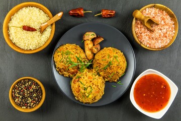 Red risotto with tomato and chili on black plate. Traditional meal. Home cooking. Spicy food. Chicken and pork in risotto.