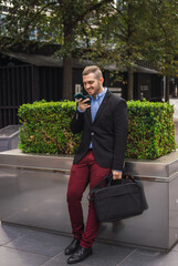 Photo of a young and attractive business man wearing smart casual clothes sending an audio with is phone in a job break