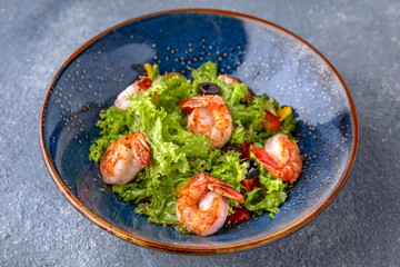 A light, nutritious salad of shrimp, lettuce and olives. Natural delicious food. Greek cuisine menu. Still life in a marine style on a blue background.