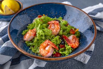 A light, nutritious salad of shrimp, lettuce and olives. Natural delicious food. Greek cuisine menu. Still life in a marine style on a blue background.