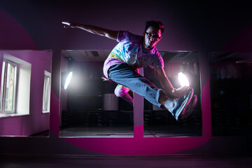 Professional break dancer in motion, practicing modern hip-hop dance in pink neon light
