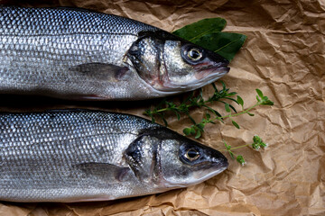 Two freshly caught sea bass on top of the brown paper.