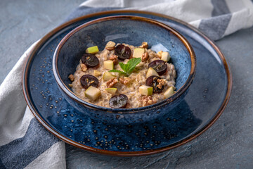 Breakfast of oatmeal with fruit. Natural delicious food. Greek cuisine menu. Still life in a marine style on a blue background.