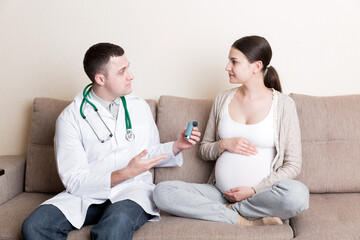 Young doctor explains pregnant woman how to use inhaler during asthmatic attack