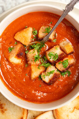 Close up overhead view of vegan tomato soup topped with croutons and parsely