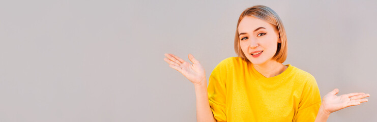 Fototapeta premium Closeup portrait, smiling, dumb clueless funny looking woman, arms asking whats the problem who cares so what, I dont know, isolated gray background. Negative human emotion, facial expression