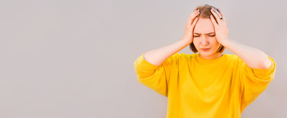 Young woman has headache, isolated on gray background