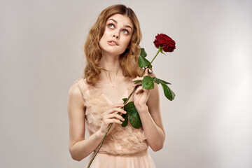 Portrait of a beautiful woman with a red rose on a beige background cropped view of an evening dress