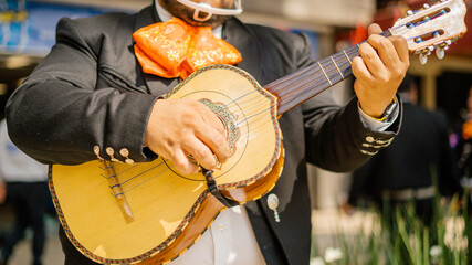 Mariachi Playing a Mexican Vihuela with Blurry Pedestrians as Background