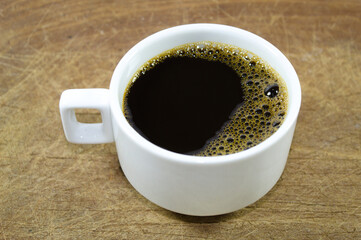 White cup of coffee on wooden background