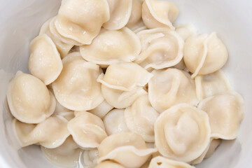 Traditional tasty boiled russian pelmeni, ravioli, dumplings with meat on white ceramic plate on grey background