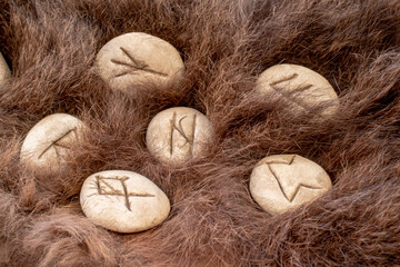 Stone runes on a animal fur. Futhark viking alphabet. Close up photo of Norse runes.