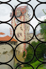 Medieval clock tower viewed through old glass window with circles