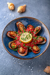 Mussels in a spicy tomato sauce. Natural delicious food. Greek cuisine menu. Still life in a marine style on a blue background.