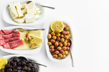 Olive varieties,cheese and salami breakfast plates designed on white surface with large copy space