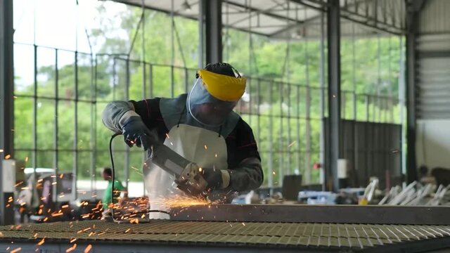 Worker wearing PPE griding metal frame