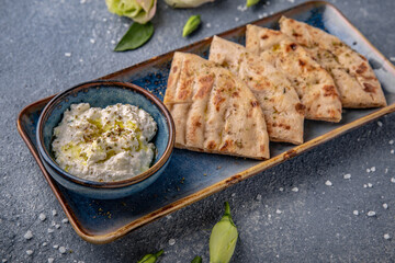 Cottage cheese appetizer sauce with garlic and olive oil with pita. Natural delicious food. Greek cuisine menu. Still life in a marine style on a blue background.