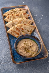 Eggplant appetizer sauce with pita. Natural delicious food. Greek cuisine menu. Still life in a marine style on a blue background.