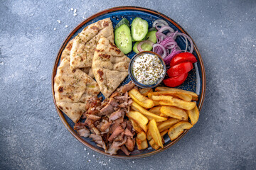 Pita shawarma with olive oil, meat, potatoes and vegetables. Natural delicious food. Greek cuisine menu. Still life in a marine style on a blue background.