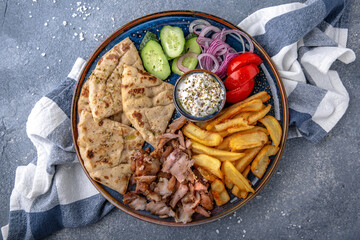 Pita shawarma with olive oil, meat, potatoes and vegetables. Natural delicious food. Greek cuisine menu. Still life in a marine style on a blue background.