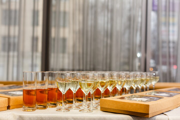 White wine being poured into wine glass in restaurant. Set of glasses with juice