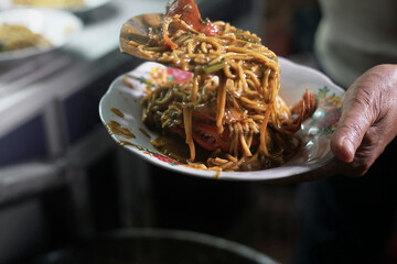 Vendor preparing Fired Seafood Noodle curry with crab and  at street food market
