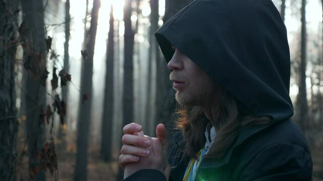 Man Warms Hands. Wanderer in Black Cloak Cowl Traveling in Misty Forest. Autumn Morning. 2x Slow motion 60 FPS
