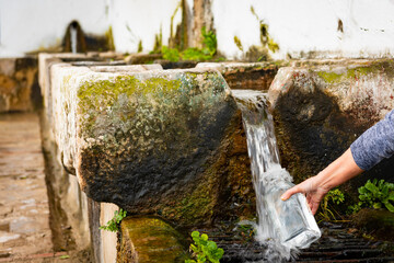 Mano llenando una botella de agua en la fuente de la Salada, ubicada en Alcalá de los Gazules,...