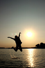 Teenage girl jumping outdoors, sunset background. People, travel, nature concept.