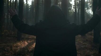 Monk Raising Hands in Prayer. Wanderer Pilgrim in Black Cloak with Cowl Praying in Misty Wood. Autumn Morning. 2x Slow motion 60 FPS
