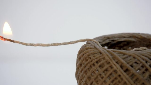 Close up view of a slowly burning hemp wick, leading up to a large ball of natural wick.  Concept showing time running out, material being used up.