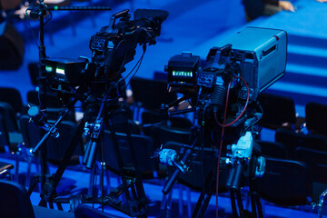 Professional camcorder, video camera on tripod, black silhouette on blue background